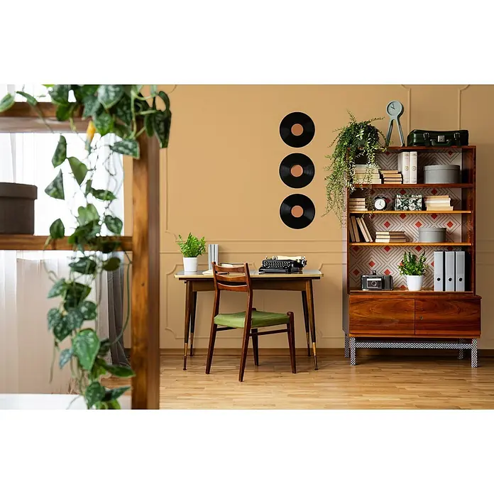 Livingwalls Wandfarbe Orange Happy Honey 5006 2,5l - Matt, 2,5 l - Ein Arbeitszimmer im Mid-Century-Stil mit Holzschreibtisch, grün gepolstertem Stuhl und Bücherregal voller Bücher und Pflanzen.