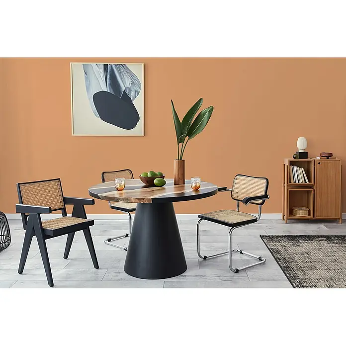 Livingwalls Wandfarbe Orange Dusty Orange DD126143 2,5l - Orange, Matt, 2,5 l - Runder Esstisch mit Holzplatte und schwarzem Kegelfuß, umgeben von modernen Stühlen mit Rattan-Sitzflächen und -Rückenlehnen.