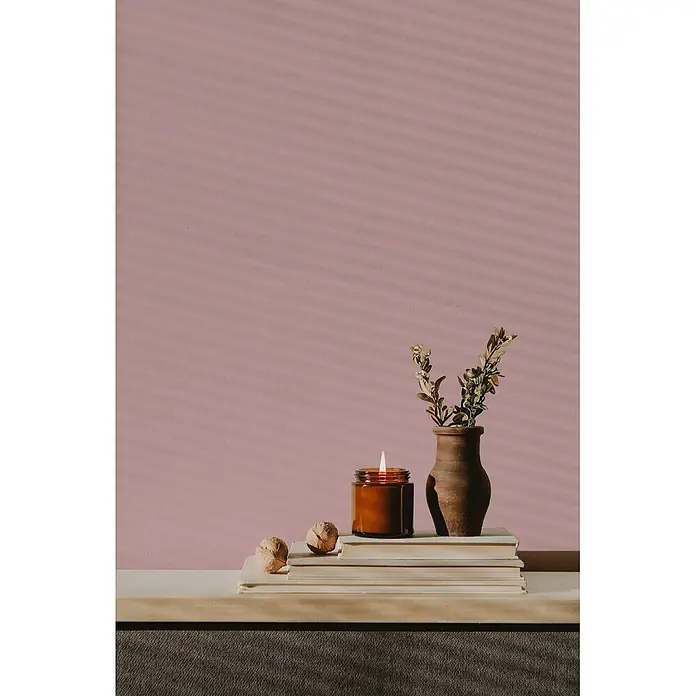 Livingwalls Wandfarbe Pink Peachy Pink DD125864 2,5l - Pink, Matt, 2,5 l - Eine brennende Kerze in einem Bernstein-Gefäß und eine rustikale Vase mit Grünzeug stehen auf gestapelten Büchern, neben Walnüssen, als gemütliche Dekoration.