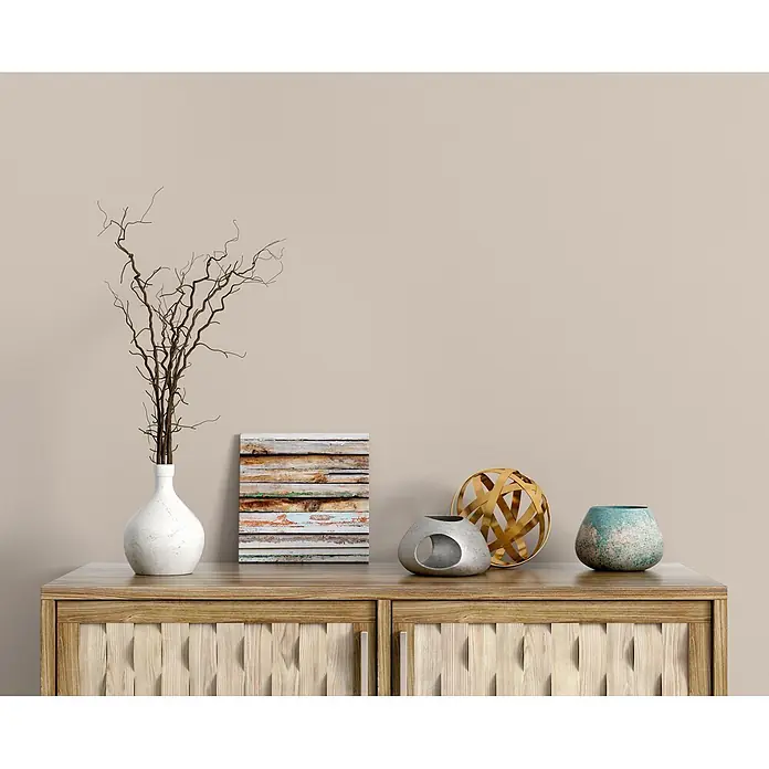 Livingwalls Wandfarbe Beige Pure Potato 6018 5l - Matt, 5 l - Ein hellbrauner Konsolenschrank mit strukturierten Türen, dekoriert mit Vasen, Ästen und Skulpturen.