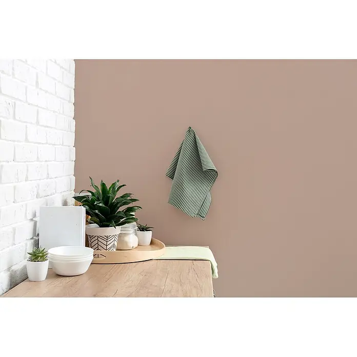 Livingwalls Wandfarbe Braun Icy Chocolate 7001 2,5l - Braun, Matt, 2,5 l - Küchenszene mit weißen Schalen, Pflanzen und grün gestreiften Handtüchern auf einer Holztheke, neben einer weißen Ziegelwand.