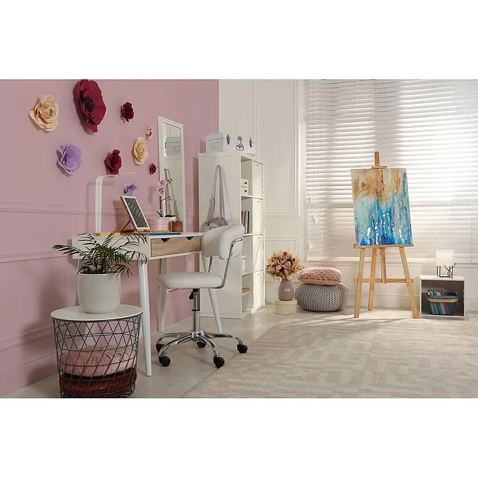 Livingwalls Wandfarbe Rosa Lovely Rose DD125800 1l - Rosa, Matt, 1 l - Ein gemütlicher, heller Raum mit einem weißen Schreibtisch und Stuhl, dekoriert mit Papierblumen und einer Staffelei mit einem Gemälde, schafft einen einladenden Arbeitsplatz.