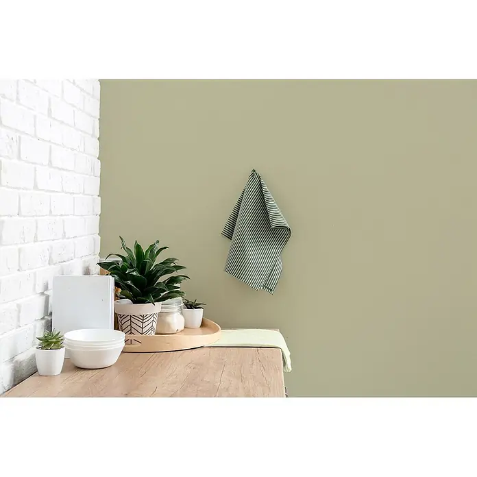 Livingwalls Wandfarbe Grün Warm Wasabi 4001 2,5l - Matt, 2,5 l - Holzarbeitsplatte mit Topfpflanzen, weißen Schalen und einem Holztablett. Zwei grün gestreifte Handtücher sind ausgestellt, eines auf der Oberfläche und eines hängend.