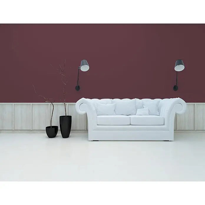 Livingwalls Wandfarbe Rot Lovely Rose DD125814 5l - Rot, Matt, 5 l - Ein weißes Chesterfield-Sofa mit Kissen vor dunkelroter Wand und heller Holzvertäfelung, flankiert von Wandleuchten und Deko-Ästen.