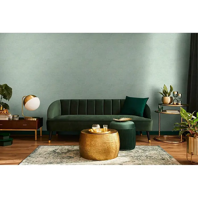 Livingwalls Vliestapete Uni, hellgrün -  - Eleganter grüner Samtsofa in einem modernen Wohnzimmer, mit goldenen Akzenten und Pflanzen.