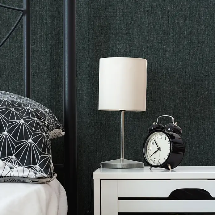 Livingwalls Vliestapete Uni, schwarz - 10.050 x 530 mm - Dunkelgrüne strukturierte Tapete an einer Schlafzimmerwand hinter Bett und Nachttisch, die eine gemütliche Atmosphäre schafft.