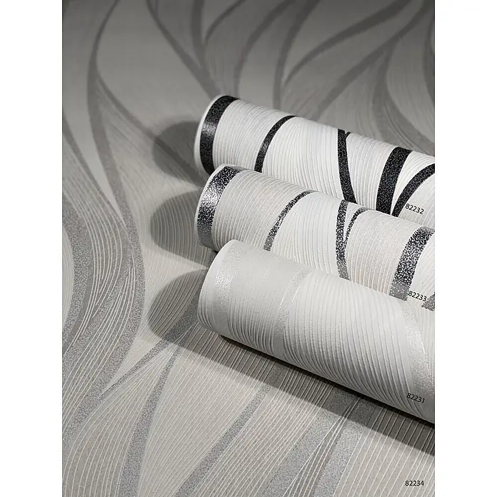 Livingwalls Vliestapete Grafisch, beige - beige, 10.050 x 530 mm - Drei strukturierte weiß-graue Tapetenrollen mit wellenförmigen Glitzermustern, auf passender Fläche gezeigt.
