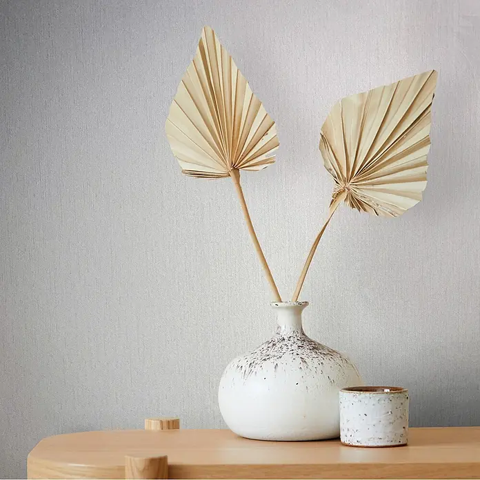 Livingwalls Vliestapete Struktur, weiß - 10.050 x 530 mm - Zwei getrocknete beige Palmenblätter in einer gesprenkelten weißen Keramikvase auf einem hellen Holztisch, mit passender Keramiktasse.