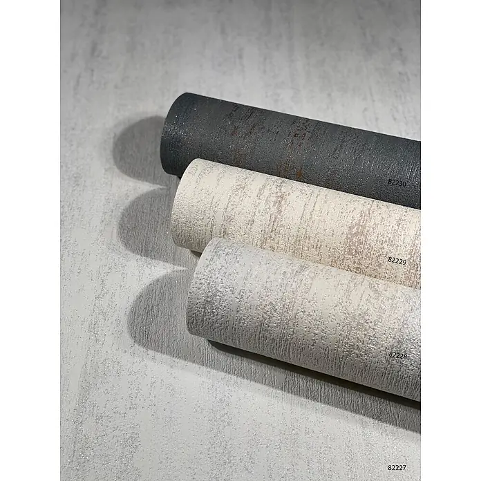 Livingwalls Vliestapete Struktur, weiß - weiß, 10.050 x 530 mm - Drei strukturierte, glitzernde Tapetenrollen in Dunkelgrau, Beige und Hellgrau, auf passendem Untergrund präsentiert.