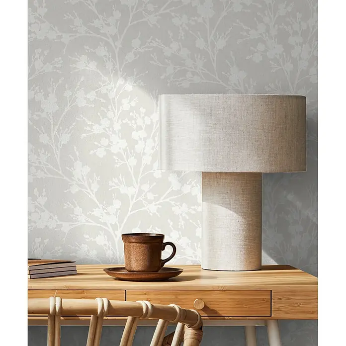 Livingwalls Vliestapete Floral, greige - 10.050 x 530 mm - Hellgraue Tapete mit zartem weißem Blütenzweigmuster, die eine Wand in einem Raum schmückt.