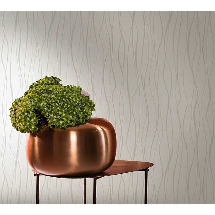 Livingwalls Vliestapete Welle, weiß -  - Eine große, runde Vase aus metallischem Kupfer mit grünen Blumen auf einem kleinen, dunklen Kupferbeistelltisch.