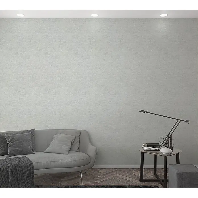 Livingwalls Vliestapete Uni, greige - 10.050 x 530 mm - Hellgraue strukturierte Wand in einem modernen Wohnzimmer mit Sofa und Beistelltisch.