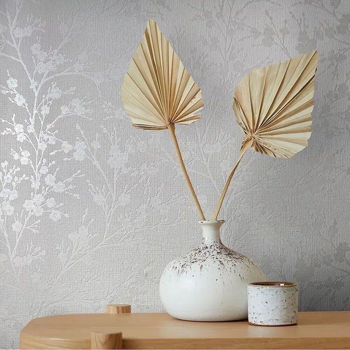 Livingwalls Vliestapete Floral, weiß -  - Eine weiß gesprenkelte Keramikvase mit getrockneten Palmenblättern und passender kleiner Tasse auf hellem Holz.