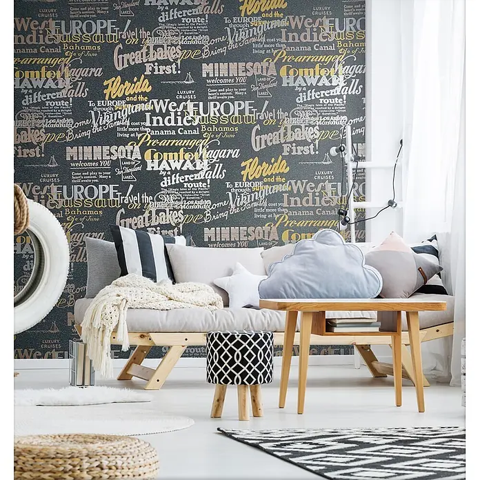 Livingwalls Vliestapete Grafisch, schwarz - 10.050 x 530 mm - Gemütliche Lounge-Ecke mit hellem Holzsofa, verschiedenen Kissen, einem kleinen Beistelltisch und einem schwarz-weiß gemusterten Hocker.