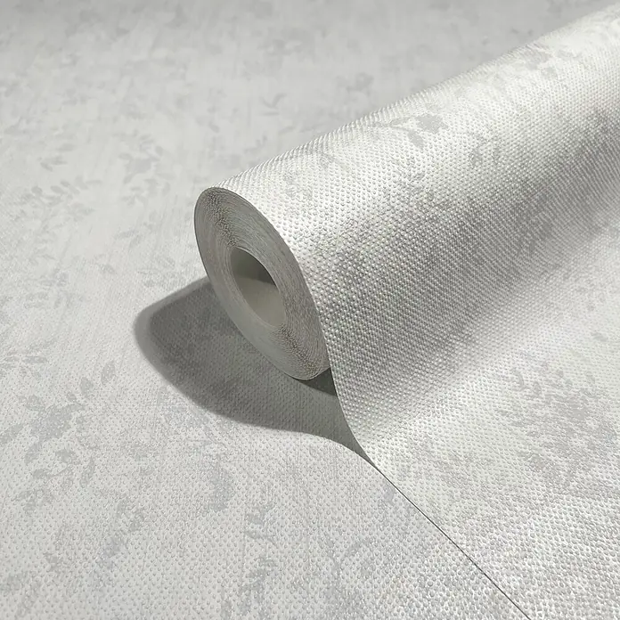 Livingwalls Vliestapete Grafisch, weiß - 10.050 x 530 mm - Heller, strukturierter Tapetenrolle in Grau mit dezentem Blumenmuster, teilweise abgerollt, um die punktierte Oberfläche zu zeigen.