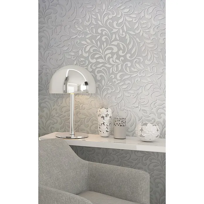 Livingwalls Vliestapete Grafisch, hellgrau, pearl - 10.050 x 530 mm - Silberne Kuppeltischlampe auf weißem Regal mit blumigem Dekor, neben einem hellgrauen Sessel.