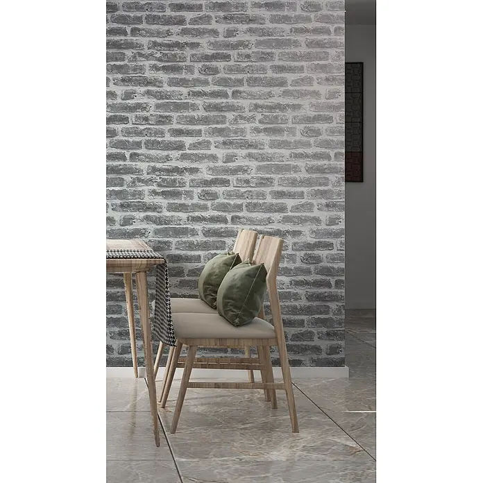 Livingwalls Vliestapete Steinoptik, greige - 10.050 x 530 mm - Graue Ziegelwandstruktur in einem modernen Essbereich mit Holzstühlen und Tisch.