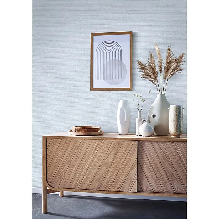 Livingwalls Vliestapete Uni, blau-weiß - 10.050 x 530 mm - Holz-Sideboard mit schrägen Paneeltüren, heller Holzoptik und Dekoartikeln oben.