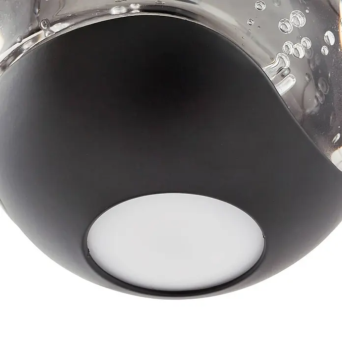 Lucande Pendelleuchte Hayley - klar / transparent, klar, Schwarz - Nahaufnahme einer dunklen, gebogenen Leuchte mit runder weißer LED-Lampe und klarer, blasiger Glasoberseite.