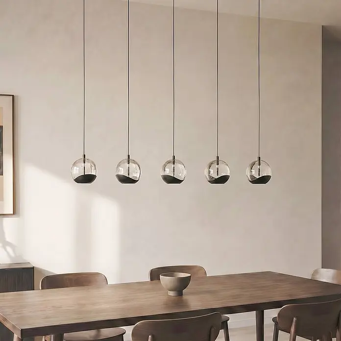 Lucande Pendelleuchte Hayley - klar / transparent, klar, Schwarz - Fünf Glas- und Schwarzpendelleuchten hängen in einer Reihe über einem Esstisch aus Holz.