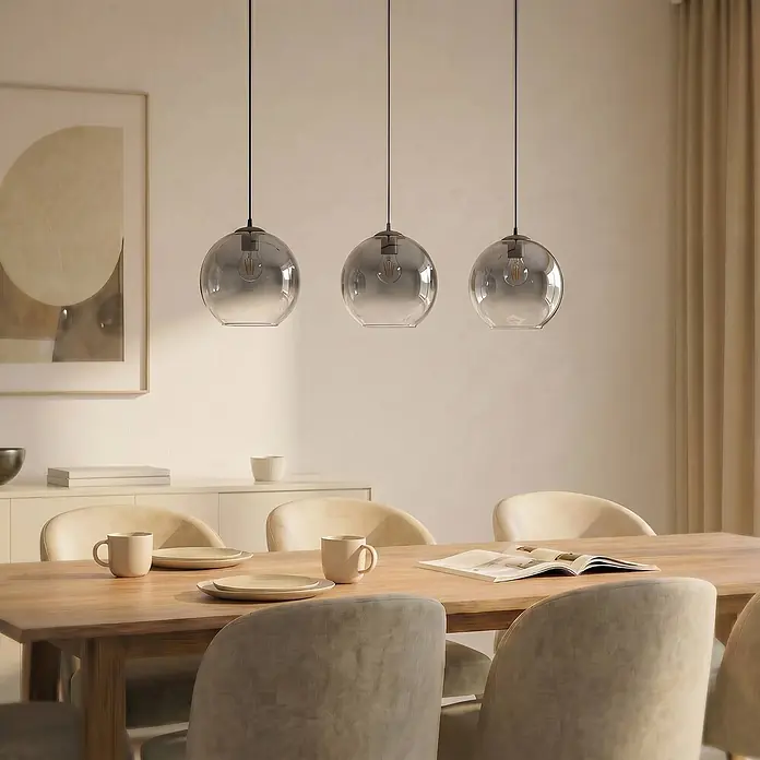 Lucande Pendelleuchte Brillar - L x B x H: 128 x 30 x 26,5 cm, alu / grau / zink, rauchgrau, zementgrau, E27 - Drei kugelförmige Pendelleuchten aus Rauchglas mit sichtbaren Glühbirnen, über einem Holzesstisch aufgehängt.