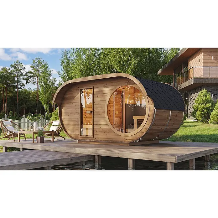 Weka Saunahaus Keila - L x B x H: 240 x 405 x 220 cm, Natur, Mit 9 kW Ofen mit integrierter Steuerung - Eine hölzerne Fasssauna mit schwarzem Schindeldach und Glastüren, auf einer Holzterrasse über einem Gewässer.