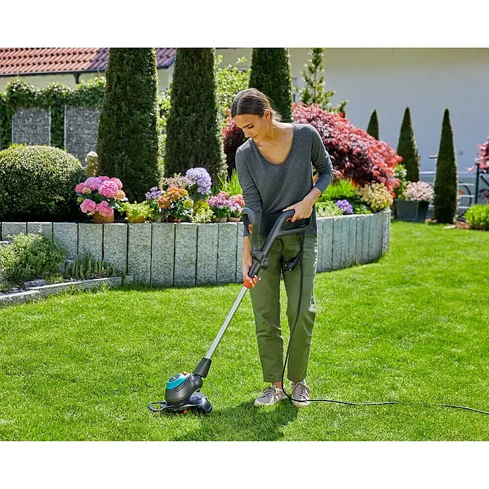 Gardena Elektro-Rasentrimmer EasyCut 450/25 - 450 W, Schnittbreite Faden: 25 cm - Frau benutzt einen GARDENA Rasentrimmer im Garten, um den Rasen zu pflegen. Das Gerät sorgt für einen präzisen Schnitt an Rasenkanten.