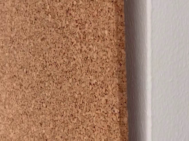 Korkwand wird an die Wand gehalten