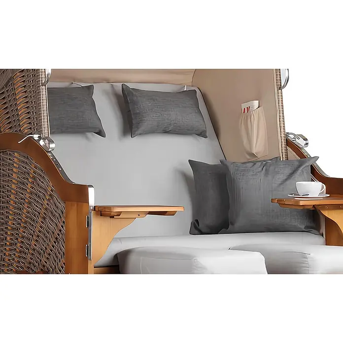 Mr. Deko Strandstuhl Strandkorb Schleswig - Pinienholz. Polyrattan, Rückenlehne verstellbar, PE Mokka, B x T x H: 120 x 80 x 160 cm - Innenausstattung eines Strandkorbs mit braunem Geflecht, hellem Holz, grauen Kissen, weißem Polster und kleinen Beistelltischen. Eine Tasse steht auf einem Tisch.