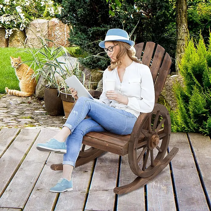 Outsunny Garten-Schaukelstuhl - 1 Stk., Tannenholz, Dunkelbraun, B x T x H: 88 x 88 x 92 cm - Dunkler Holzschaukelstuhl mit Wagenrad-Akzenten, von einer Frau zum Entspannen auf einer Terrasse genutzt.