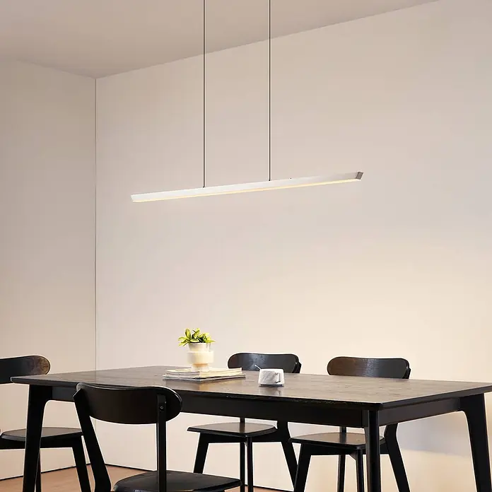 Lucande Pendelleuchte Solvar - chrom / silber, silber - Weiße lineare LED-Pendelleuchte über einem dunklen Esstisch.