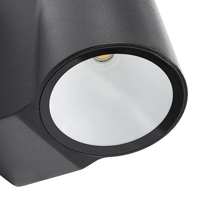 Lindby Außenwandleuchte Illuvia - schwarz, schwarz, IP44 - Nahaufnahme eines schwarzen, texturierten Außenstrahlers mit weißem Reflektor und warmer LED-Lichtquelle.