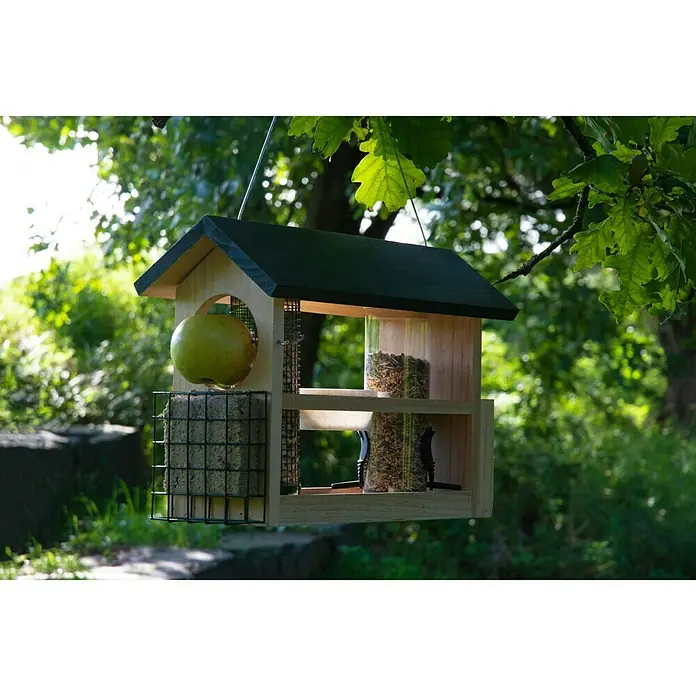 Dobar Futterstation 7-in-1 - 39 x 19 x 29 cm, Natur/Grün - Ein vielseitiges Holz-Vogelhaus mit Futterstationen für verschiedene Futtersorten, inklusive Apfelhalterung und Fettblockgitter, hängt in einem Garten.