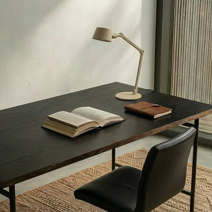Lucande Tischleuchte Silka - L x B x H: 71 x 22 x 93,5 cm, creme / amber, creme / amber, E27 - Ein dunkler Holzschreibtisch mit beiger Schreibtischlampe, offenem Buch und braunem Notizbuch. Ein schwarzer Stuhl steht am Arbeitsplatz.