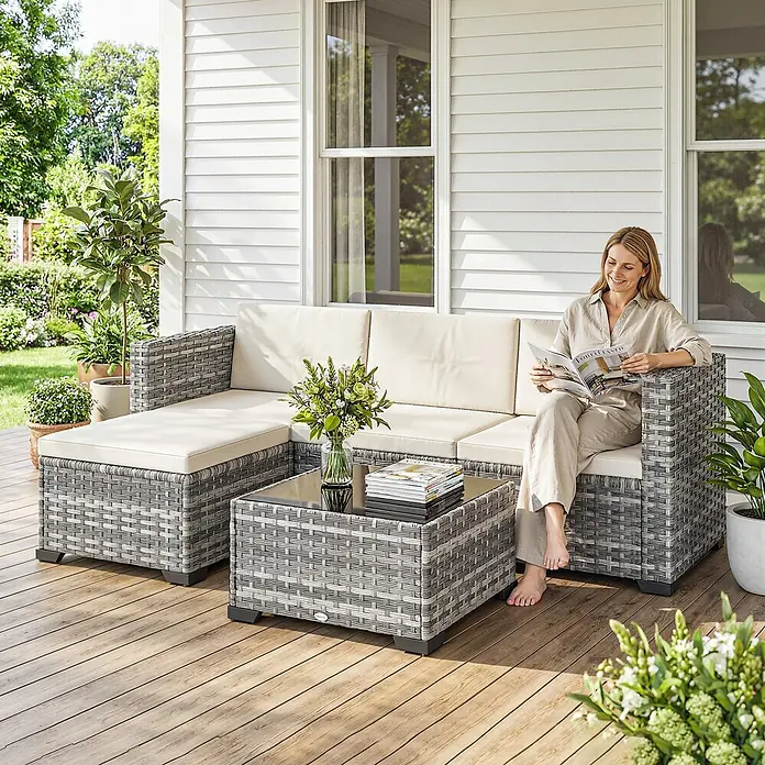 Outsunny Loungemöbel-Set mit Tisch - 5 -tlg., PE-Rattan, Grau - Graues Polyrattan-Gartensofa mit hellen Kissen und passendem Couchtisch auf einer Terrasse, eine Frau liest darauf.