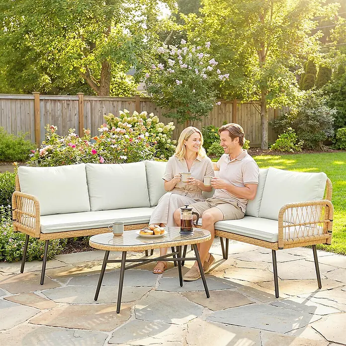 Outsunny Loungemöbel-Set - 4 -tlg., PE-Rattan, Cremeweiß - L-förmiges Garten-Schnittsofa mit hellbeigen Kissen und Rattan-Optik-Gestell, wo ein Paar Kaffee und Gebäck im Garten genießt.