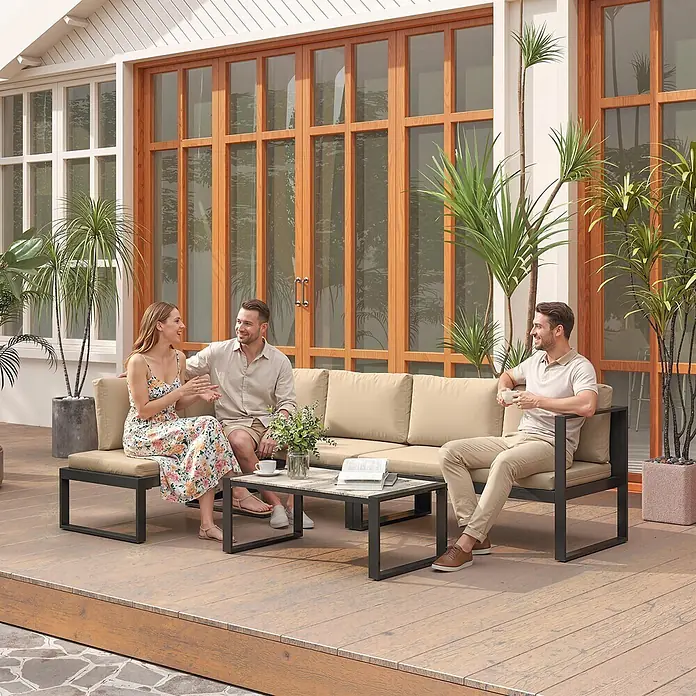 Outsunny Loungemöbel-Set - Khaki - Outdoor-Sofa mit beigefarbenen Kissen und schwarzem Metallgestell, kombiniert mit passendem Couchtisch auf einer Holzterrasse, von Personen genutzt.