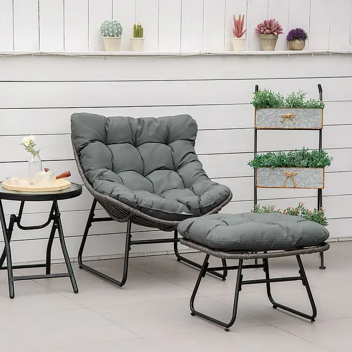 Outsunny Loungemöbel-Set - PE-Rattan - Grauer gepolsterter Rattan-Loungesessel mit Metallrahmen, passendem Hocker und Beistelltisch auf einer Terrasse.