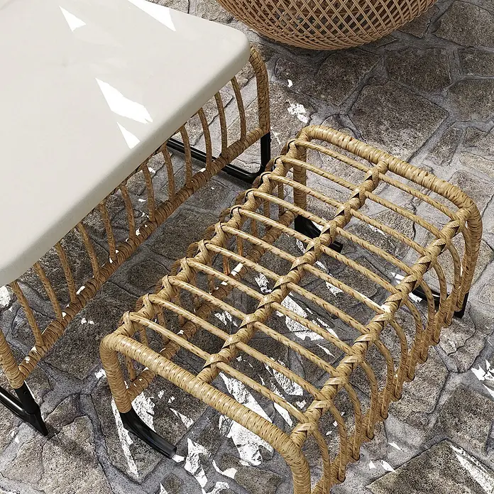 Outsunny Loungemöbel-Set - PE-Rattan, Cremeweiß - Nahaufnahme eines hellen Korbmöbel-Sets (Tisch mit weißem Kissen, passender Hocker) auf einer Steinterrasse.