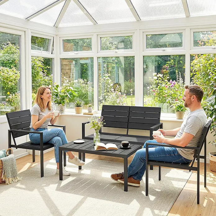 Outsunny Loungemöbel-Set - Polyethylen hoher Dichte (PE‑HD), Schwarz - Dunkelgraue Gartenmöbelgarnitur mit zwei Stühlen, einem Sofa und einem Couchtisch, von zwei Personen in einem hellen Wintergarten genutzt.