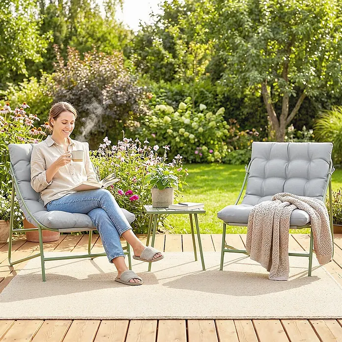 Outsunny Loungemöbel-Set - Hellgrau - Zwei hellgraue Outdoor-Loungesessel mit grünen Gestellen und einem kleinen grünen Beistelltisch auf einer Holzterrasse im Garten, einer davon von einer lesenden Frau besetzt.