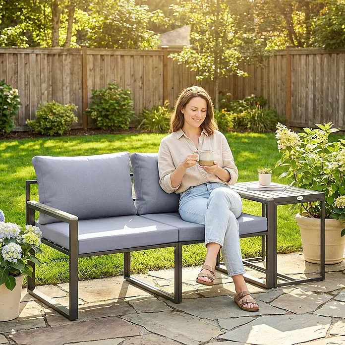 Outsunny Loungemöbel-Set - Grau - Graue Outdoor-Loungegruppe mit dunklem Metallrahmen und integriertem Beistelltisch, im Garten genutzt.