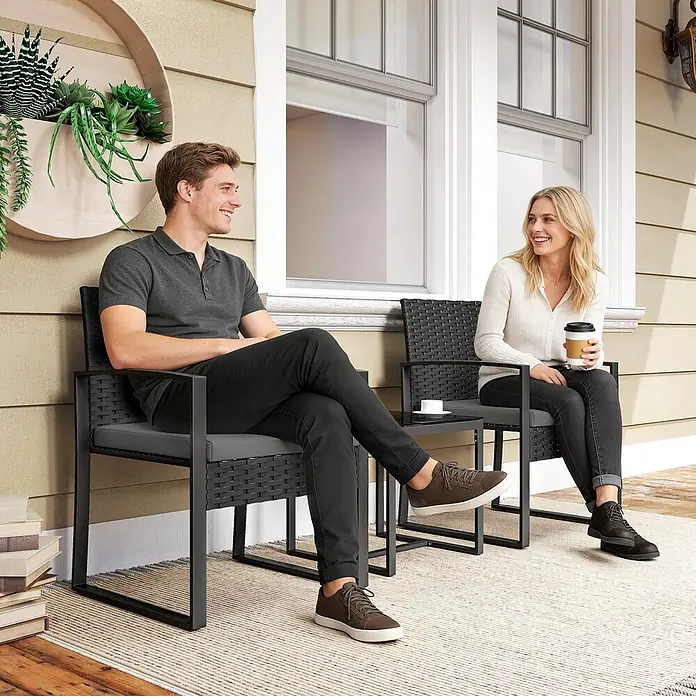 Outsunny Loungemöbel-Set - PE-Rattan, Dunkelgrau - Kompaktes Outdoor-Bistro-Set aus dunklem Rattan und Metall mit grauen Kissen, bietet bequem Platz für zwei auf einer Terrasse.