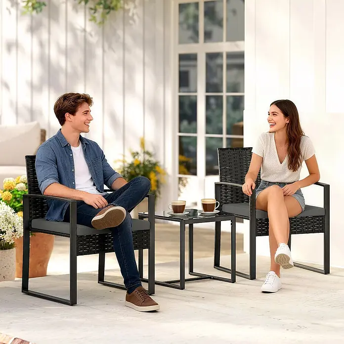 Outsunny Loungemöbel-Set - PE-Rattan, Dunkelgrau - Zwei Personen genießen Kaffee auf einem schwarzen Rattan- und Metall-Loungeset mit grauen Polstern, zwei Stühlen und Glastisch auf einer hellen Terrasse.
