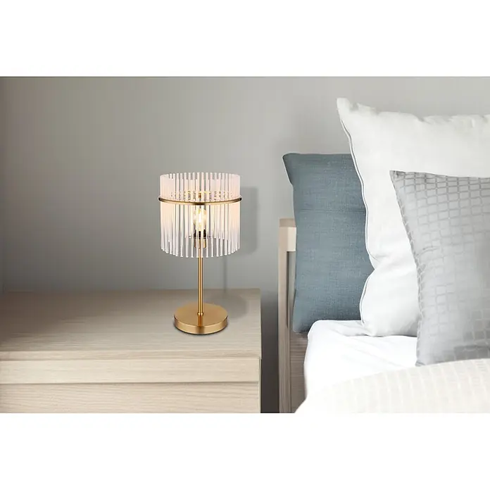 Globo Tischleuchte Gorley - 60 W, E27 - Goldene Tischlampe mit transparentem geriffeltem Schirm auf einem Nachttisch neben einem Bett.