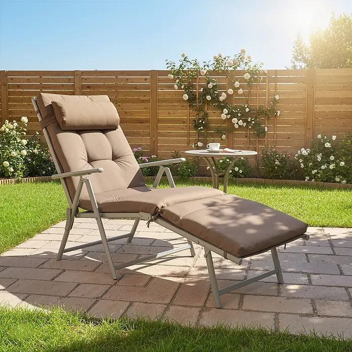 Outsunny Gartenliege - B x T: 63,5 x 190 cm, Braun, Metall, Rückenlehne verstellbar - Braun gepolsterte Gartenliege mit grauem Gestell und Beistelltisch in einem sonnigen Garten.