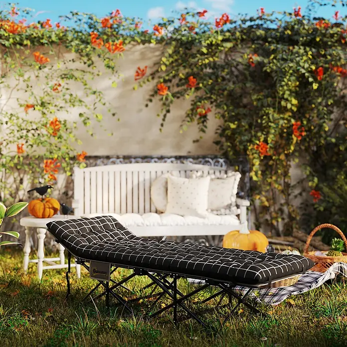 Outsunny Campingliege - Schwarz, Metall - Schwarzes Klappbett mit weißem Gittermuster-Kissen, in einem Garten für Entspannung im Freien aufgestellt.