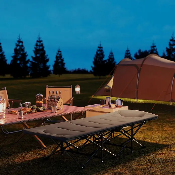 Outsunny Campingliege - Grau, Metall - Grau gepolstertes Campingbett mit schwarzem Klapprahmen, nachts im Freien neben Campingtisch und Zelt aufgebaut.