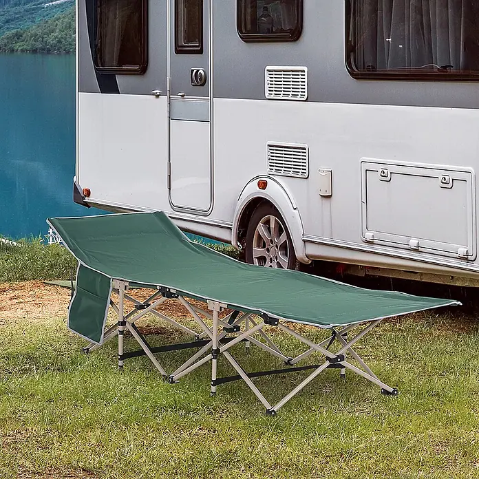 Outsunny Campingliege - Grün, Stahl, Klappbar - Ein grünes Campingbett mit hellem Metallgestell steht auf Gras neben einem Wohnwagen, bereit für die Erholung im Freien.