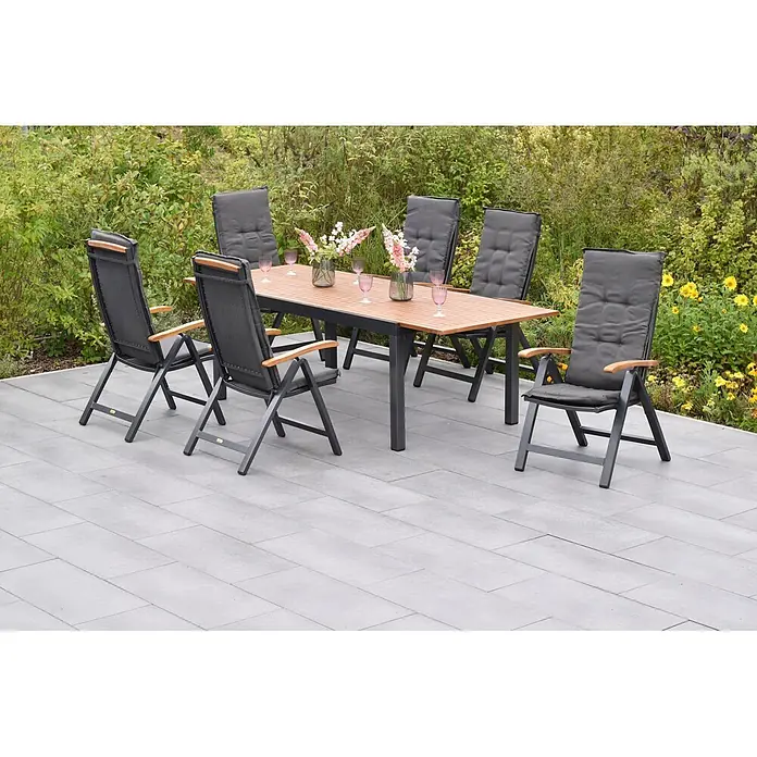 Merxx Gartentisch-Set Tilos - Gesamtumfang: 13 -tlg., Aluminium/Akazie, Klappbar - Outdoor-Essgruppe: ein Holztisch mit sechs klappbaren dunklen Stühlen, Polstern und Holzarmlehnen auf einer Terrasse.